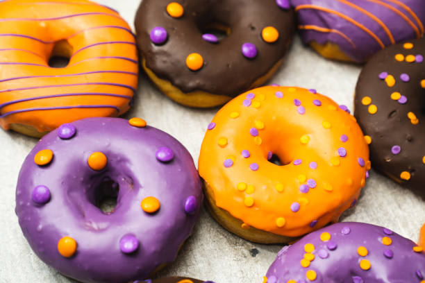 istock donuts background for halloween tiled on light wooden texture background 1344594891