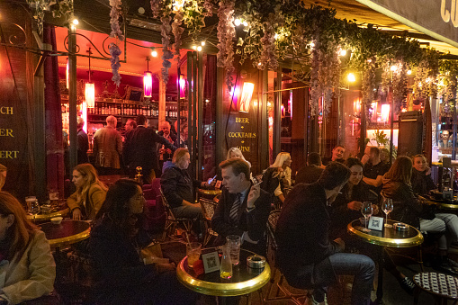 Terrace and café near the Arc de Triomphe in Paris in the evening. People are sitting on the terrace talking and drinking. Photo was taken at restaurant La Flamme on the Avenue de Wagram, 75008 Paris, France