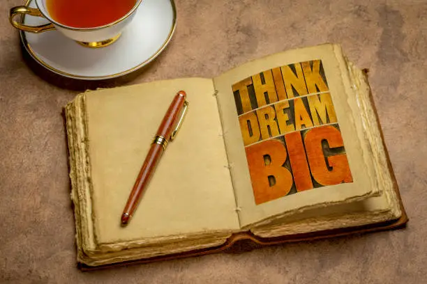 think and dream big motivational phrase -  word abstract in letterpress wood type printing blocks in a retro journal with a cup of tea