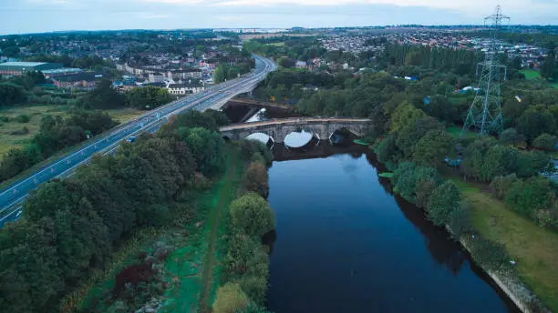 Aerial view of calm river with stone bridge carrying old great north road across River Aire