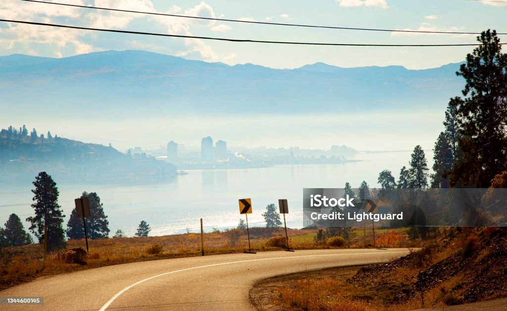 Westside Road to Kelowna British Columbia Winding Westside Road curves around the mountain, with a foggy Kelowna across the lake in the background Kelowna Stock Photo