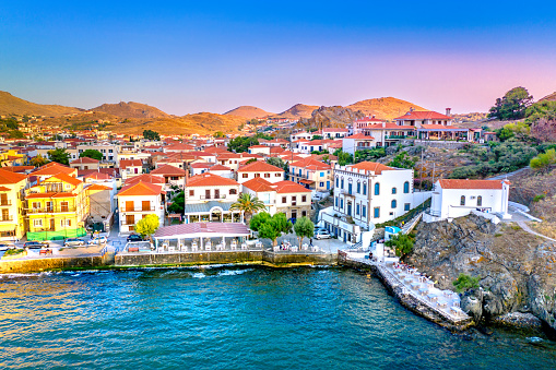 Wide-angle view of Eivissa’s harbour, old town and marina at sunset. Picturesque clouds, calm waters reflecting the warm light of a summer evening, a moored sailing ship and fast ferries, a long jetty, the iconic skyline of Dalt Vila dominated by the cathedral church of Santa Maria de les Neus. High level of detail, natural rendition, realistic feel. Developed from RAW.