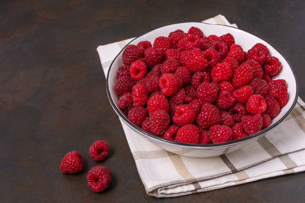 istock Red raspberry berry in plate on wooden table. 1344605050