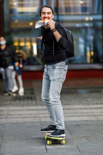 młody człowiek cieszy się deskorolką w dzielnicy miejskiej. - people eating walking fun zdjęcia i obrazy z banku zdjęć