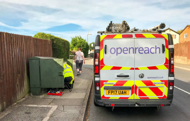 Openreach broadband va with engineer working on a telephone junction box Pontypridd, Wales - July 2018: BT engineer working on a telephone junction box alongside Openreach van parked on a street in a residential housing area british telecom photos stock pictures, royalty-free photos & images