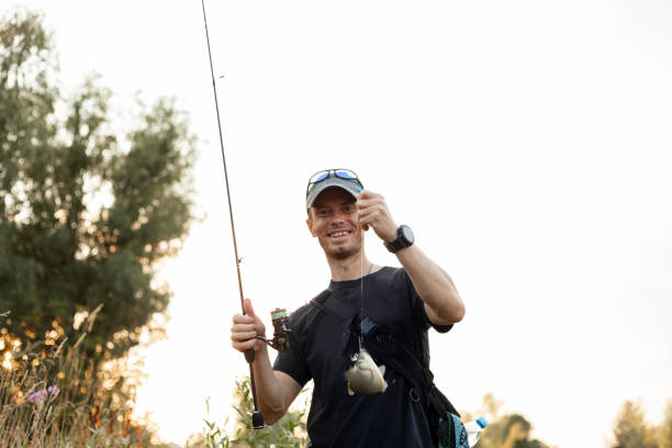 istock Happy smiling man caught a fish with a rod 1344606377