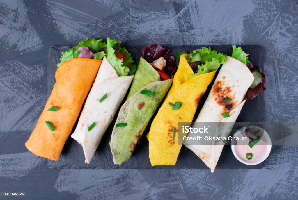 Assorted wraps with tortillas of various colors with chicken Assorted wraps with tortillas of various colors with chicken, vegetables, mushrooms, herbs and sauce on the gray table Tortilla - Flatbread Stock Photo