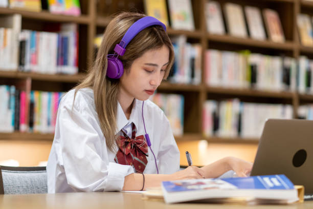 istock Young female student wearing headphone studying in the library 1344609450