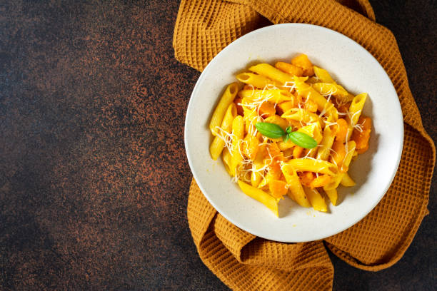 istock Neapolitan pasta penne rigate with pumpkin in a ceramic plate on a dark culinary background top view. Traditional Italian cuisine 1344613256