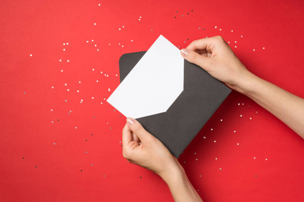 zdjęcie z góry w pierwszej osobie z rękami trzymającymi otwartą czarną kopertę z białą kartą nad cekinami na izolowanym czerwonym tle z pustym miejscem - opening mail envelope greeting card zdjęcia i obrazy z banku zdjęć