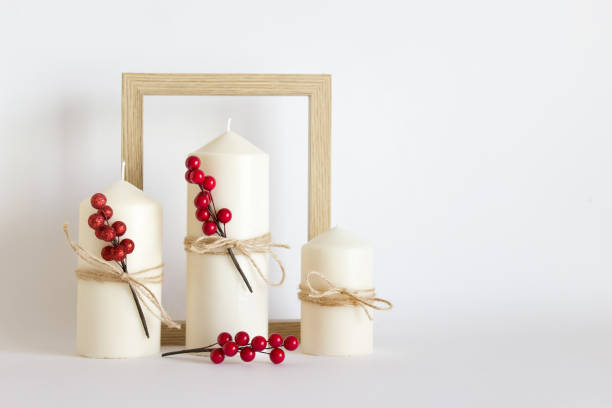 Christmas, New Year composition with three white candles, red berries and wooden frame on white background stock photo