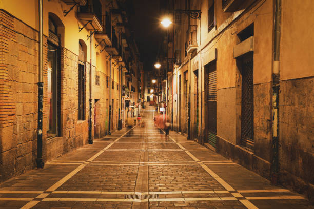 Typical small street view with shops at night in Pamplona, Spain