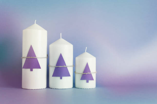 Christmas, New Year greeting card with three white candles, purple paper Christmas trees on purple background stock photo