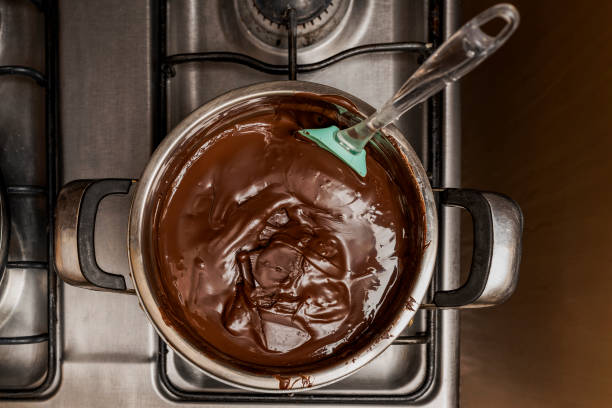 vista superior de una preparación de salsa de chocolate en una olla en la cocina para la preparación de la receta casera de alfajores argentinos - chocolate pot de creme fotografías e imágenes de stock