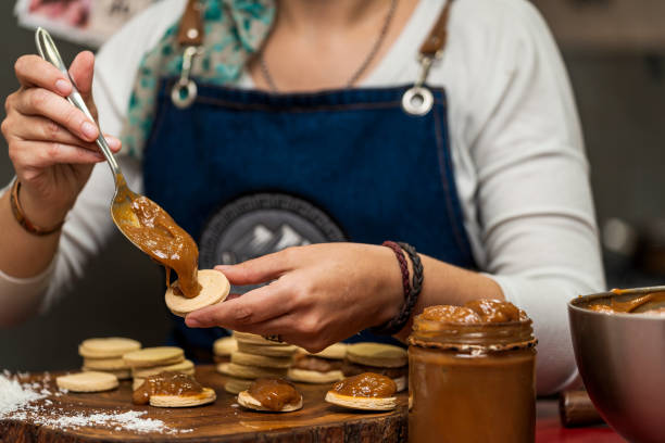 Cropped view of an unrecognizable female cook making Argentine alfajores by putting dulce de leche into dough lids Cropped view of an unrecognizable female cook making Argentine alfajores by putting dulce de leche into dough lids. Concept of regional, traditional food. dulce de leche stock pictures, royalty-free photos & images