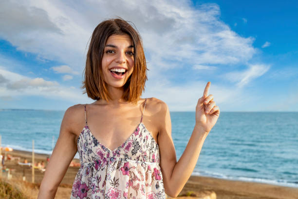 istock Young brunette with a surprise expression pointing her left hand up as to indicate something. 1344620066