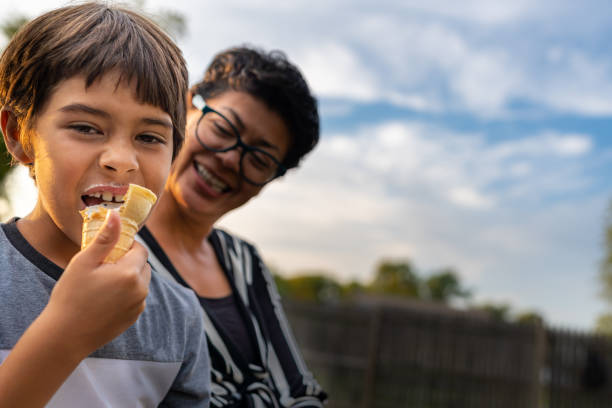 a silly boy eats ice cream while his mother watches him and laughs. - native american north american tribal culture women mature adult imagens e fotografias de stock