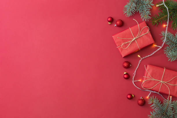 istock Flat lay frame with fir branches, christmas baubles decoration and gift box on a red background 1344624164