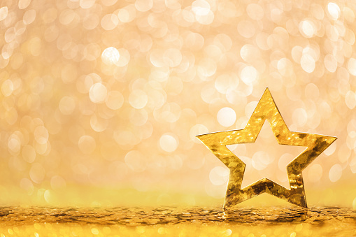 Abstract Christmas background with golden star on gold shiny glittered background. Still life photography