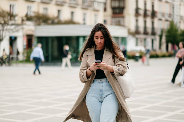 istock Young woman walking in a city while using a smart phone 1344626397