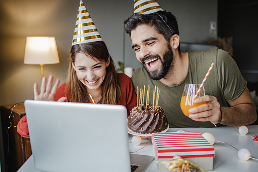 Young couple talking with friends on a video call while celebrating birthday