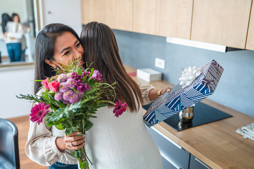 Asian Mother And Teenage Daughter Embracing And Celebrating A Birthday