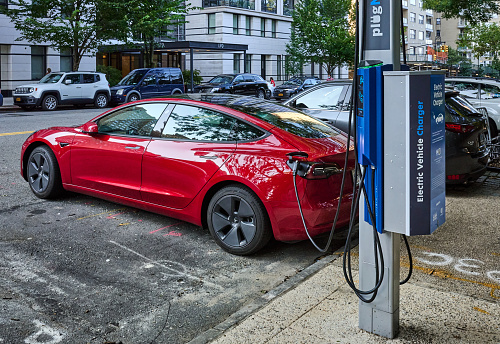 New York, NY - August 24, 2021: Recharging an electric car at a curbside NYC electric vehicle charger in the Upper East Side of NYC. This charger is provided by Flo in partnership with Con Edison and NYC DOT, (Department of Transportation)