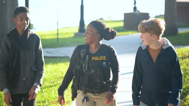 Friendly policewoman walking with two teenage boys