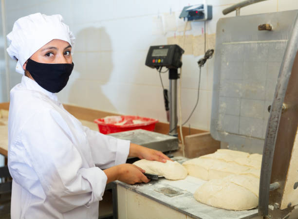 istock Woman baker dividing raw dough into portions in bakery 1344643841