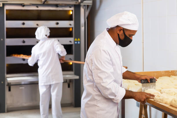 istock Baker dividing raw dough into equal parts in bakery 1344643847