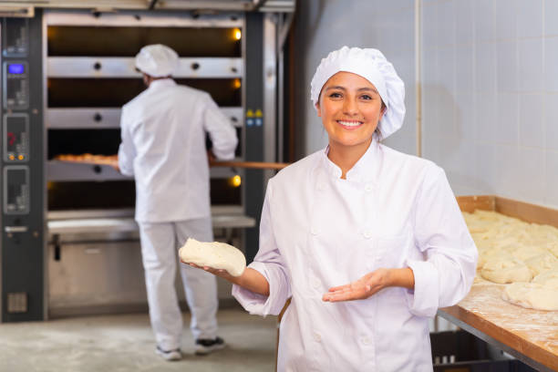 istock Woman baker smiling at camera during daily work with dough 1344643858