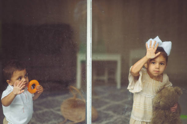istock Sad small mixed race children look out of a window 1344644443