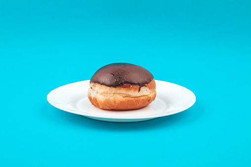 Chocolate donut on a white plate on a blue background