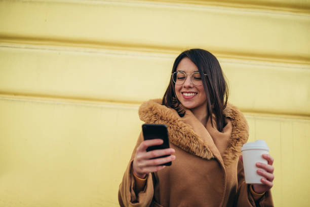 istock Young hispanic woman using smartphone and drinking coffee takeaway 1344652655