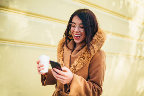 istock Young hispanic woman using smartphone and drinking coffee takeaway 1344652656