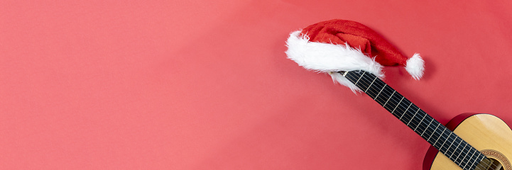 Banner with copy space Christmas guitar on a red background with Christmas Hat