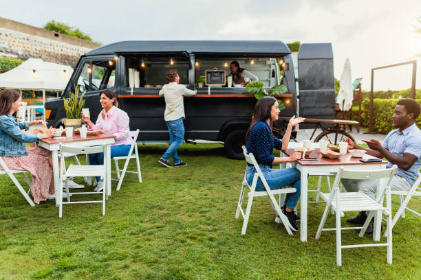 Happy multiracial people having fun eating in a food truck stock photo