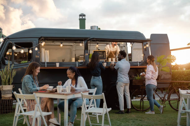 persone multirazziali felici che si divertono a mangiare in un mercato di camion di cibo di strada - food truck foto e immagini stock