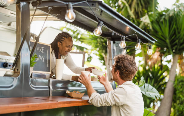 Afro food truck owner serving meal to male customer - Modern business and take away concept stock photo