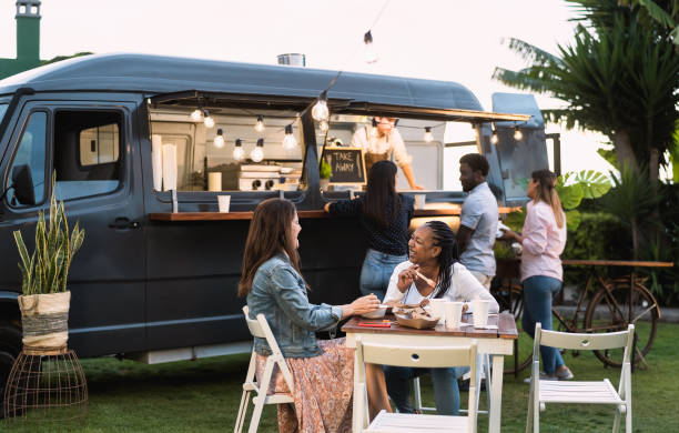 Happy multiracial people having fun eating in a street food truck stock photo