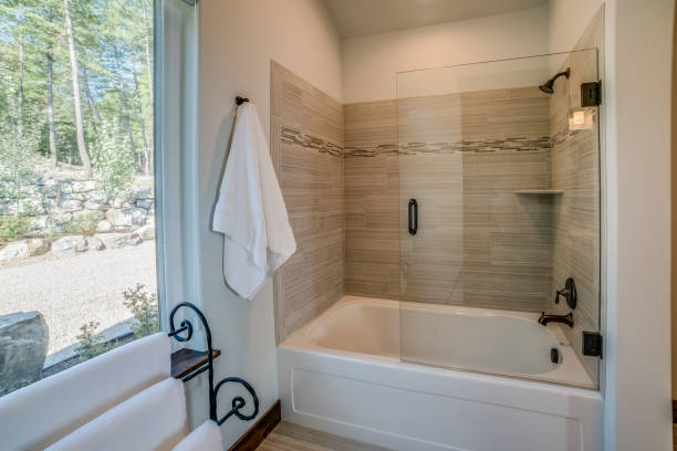 Half glass on tub shower combo White towels and large window give a light feel to this bathroom bathroom glass stock pictures, royalty-free photos & images