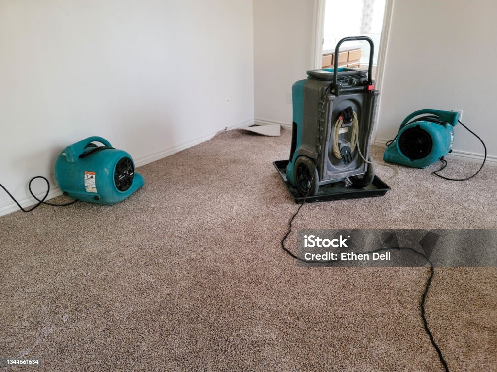 Air Movers and Dehu Two air movers and a dehumidifier drying a home. Water Stock Photo