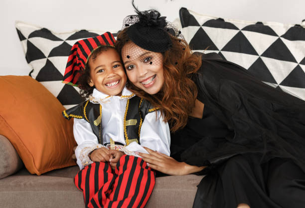 радостная афроамериканская семейная мать и маленький мальчик сын в костюмах на хэллоуин дома - women halloween thanksgiving african ethnicity стоковые фото и изображения