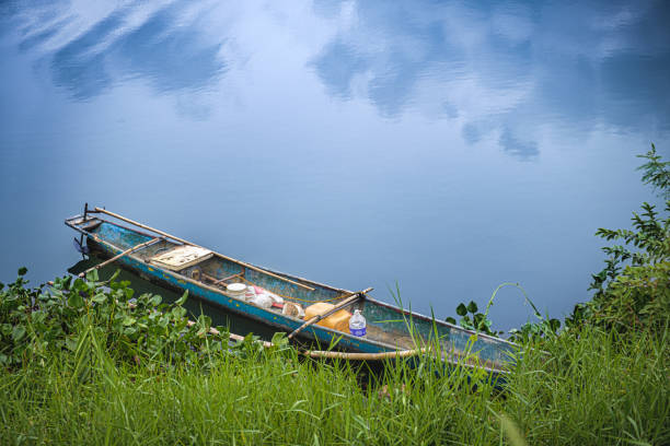 small boat moored to shore by a placid lake reflecting blue sky