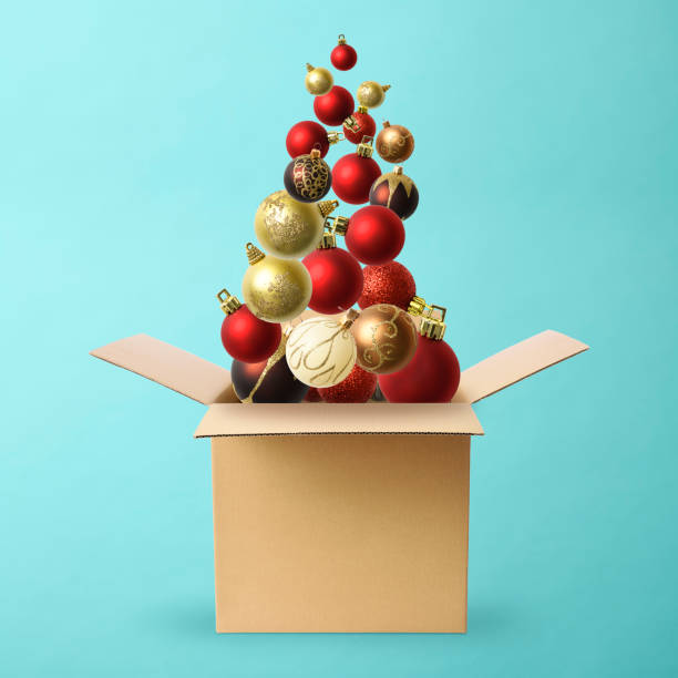Lots of Christmas ornament floating in mid-air from cube cardboard box on light blue background.