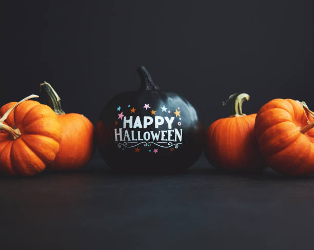 istock Black Pumpkin with Happy Halloween Message on Black Background with Orange Pumpkins 1344679636