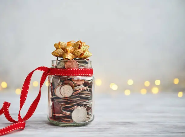 Holiday Savings Jar Filled with Coins and Christmas Ribbon and Bow