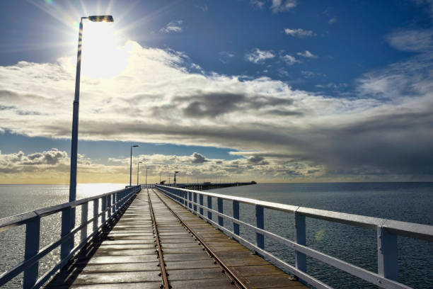 istock Busselton jetty with rail track and sun shining behing clouds 1344681766