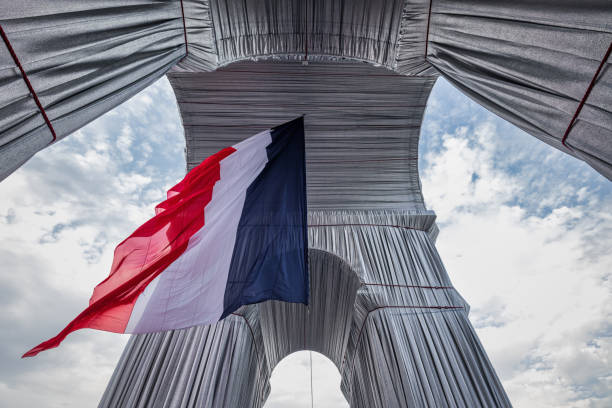 French National Flag Arc de Triomphe Wrapped by Christo Paris France Paris, France - September 25th 2021: French National Flag hanging down from Arc de Triomphe Wrapped by the artists Christo and Jean Claude. View from directly below against the Arc de Triomphe with French National Flag hanging in the middle for Sunday 25th celebration. The L'Arc de Triomphe Wrapped is a temporary artwork for Paris, on view from Saturday, September 18 to Sunday, October 3, 2021. This Art project has been realized in partnership with the Centre des Monuments Nationaux and in coordination with the City of Paris.  Place de l’Etoile - Charles de Gaulle, Paris, France, Europe french flag stock pictures, royalty-free photos & images