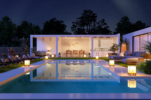 Luxury Villa Exterior At Night With Swimming Pool, Sofa And Lounge Chairs.